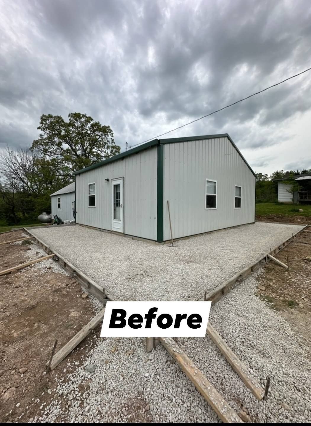 A metal building with a concrete foundation under a cloudy sky, labeled 