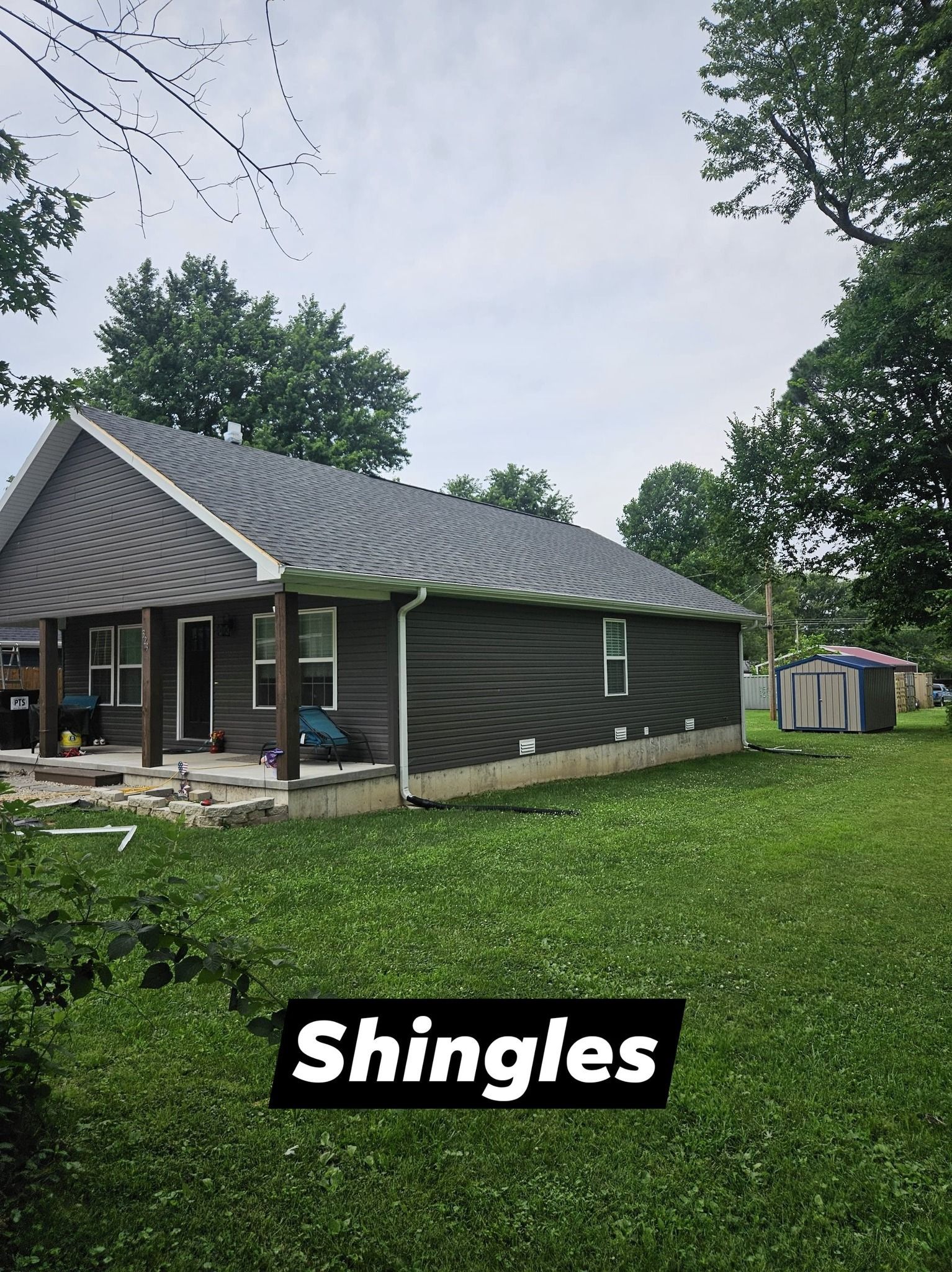 A small house with gray siding and roof in a grassy yard, with text 